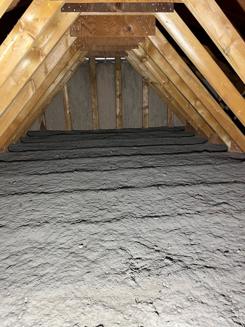 Attic with old settled insulation visible between joists